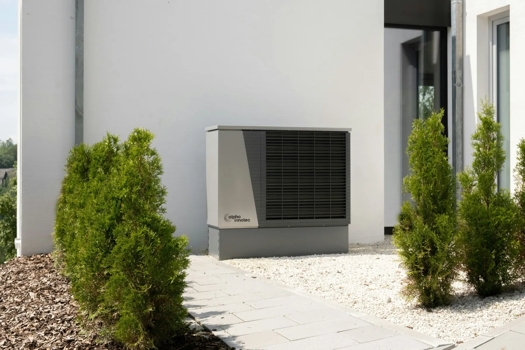 An air source heat pump unit installed outside a modern rendered house